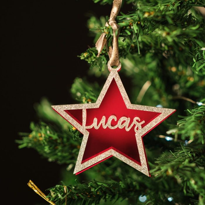 Bola de navidad personalizada colgada de un arbol de navidad verde con texto LUCAS en colores glitter plata y rojo espejo